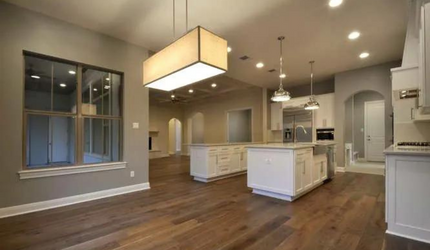 A large empty kitchen with hardwood floors and white cabinets.
