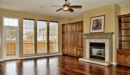 An empty living room with a fireplace and a ceiling fan