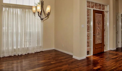 An empty dining room with hardwood floors and a chandelier.