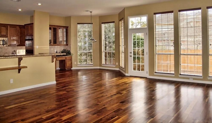 An empty living room with hardwood floors and lots of windows