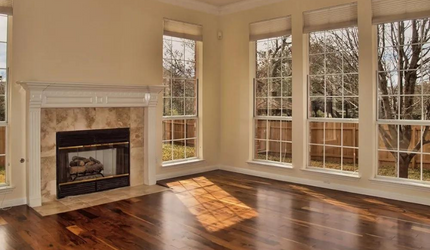 An empty living room with a fireplace and lots of windows.