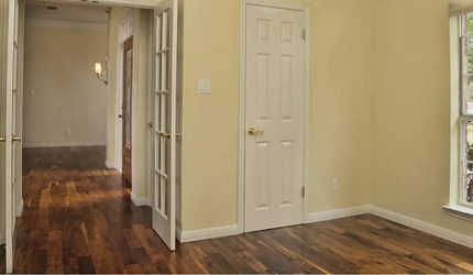 An empty room with hardwood floors and french doors.