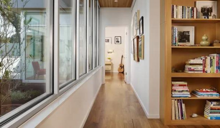A long hallway with a bookshelf and lots of windows