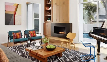 A living room with a fireplace , coffee table , chairs and a piano.