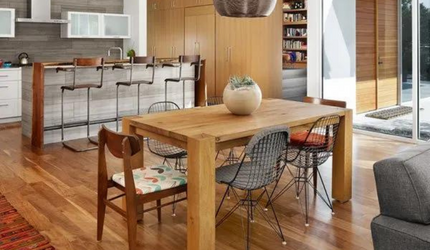 A dining room table with chairs and a vase on it in a kitchen.