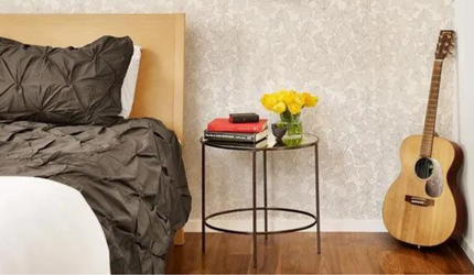 A bedroom with a bed a nightstand and a guitar