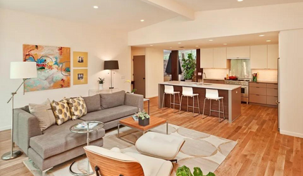 A living room with a couch , chair , coffee table and kitchen.