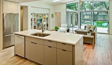 A kitchen with a large island , sink , refrigerator and dishwasher.