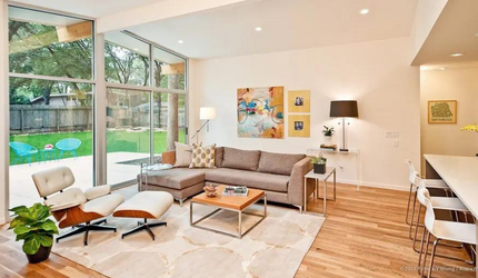 A living room with a couch , chair , coffee table and large windows.