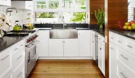 A kitchen with white cabinets and a stainless steel sink.