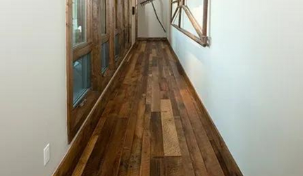A long hallway with wooden floors and a white wall.