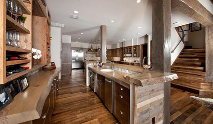 A kitchen with wooden cabinets , stainless steel appliances , a sink , and stairs.