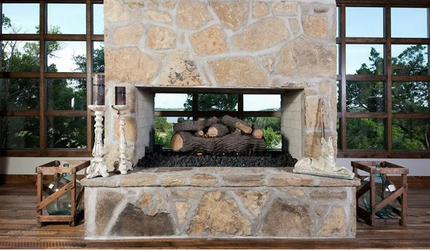 A stone fireplace with logs in it is in a living room.
