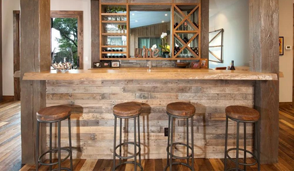 A kitchen with a wooden bar and stools.