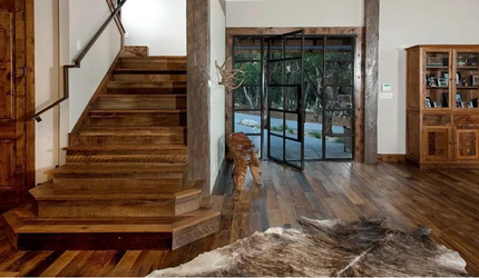 A wooden staircase in a living room with a cowhide rug on the floor.