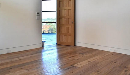 An empty room with a wooden floor and a wooden door.