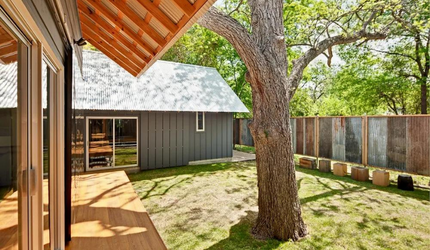 There is a large tree in the middle of the backyard of a house.