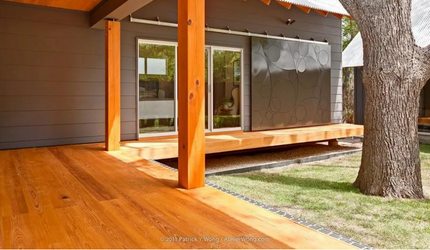 A house with a wooden deck and a tree in front of it.