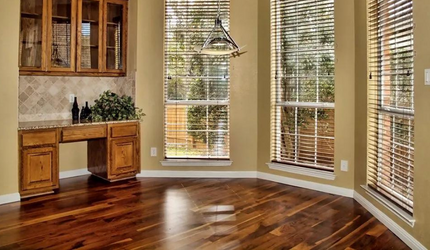 A living room with hardwood floors , a desk , and lots of windows.