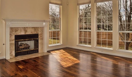 An empty living room with a fireplace and lots of windows.