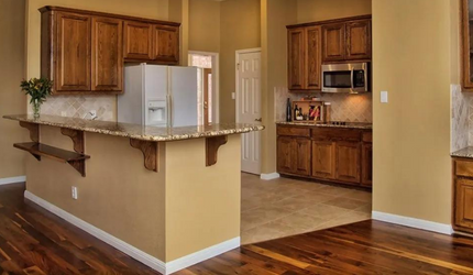 A kitchen with wooden cabinets , granite counter tops , a refrigerator and a microwave.