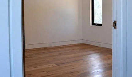 An empty room with hardwood floors and a window.