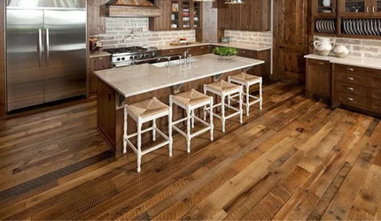 A kitchen with hardwood floors , stainless steel appliances , and a large island.
