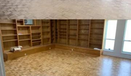 A large empty room with lots of shelves and windows.