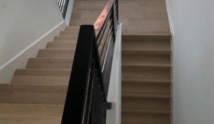 A wooden staircase with a black railing in a house.