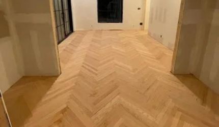 A wooden floor with a herringbone pattern in a room.