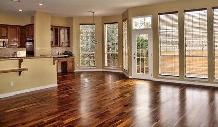 An empty living room with hardwood floors and lots of windows.
