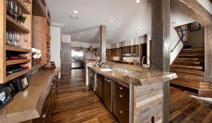 A kitchen with wooden floors , stainless steel appliances , a sink , and stairs.