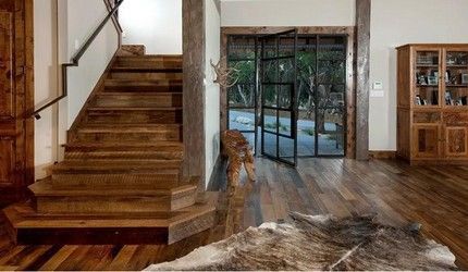 A wooden staircase in a living room with a cowhide rug on the floor.
