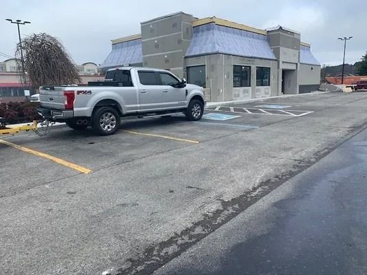 A silver pickup truck parked across two accessible parking spaces in front of a commercial building under construction.