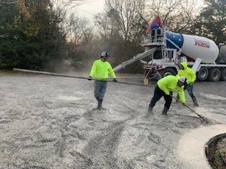 Construction workers in neon yellow shirts use a screed tool to level wet concrete poured from an SRM mixer truck.