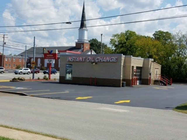 Valvoline Instant Oil Change center with a tall church steeple in the background under a blue sky.