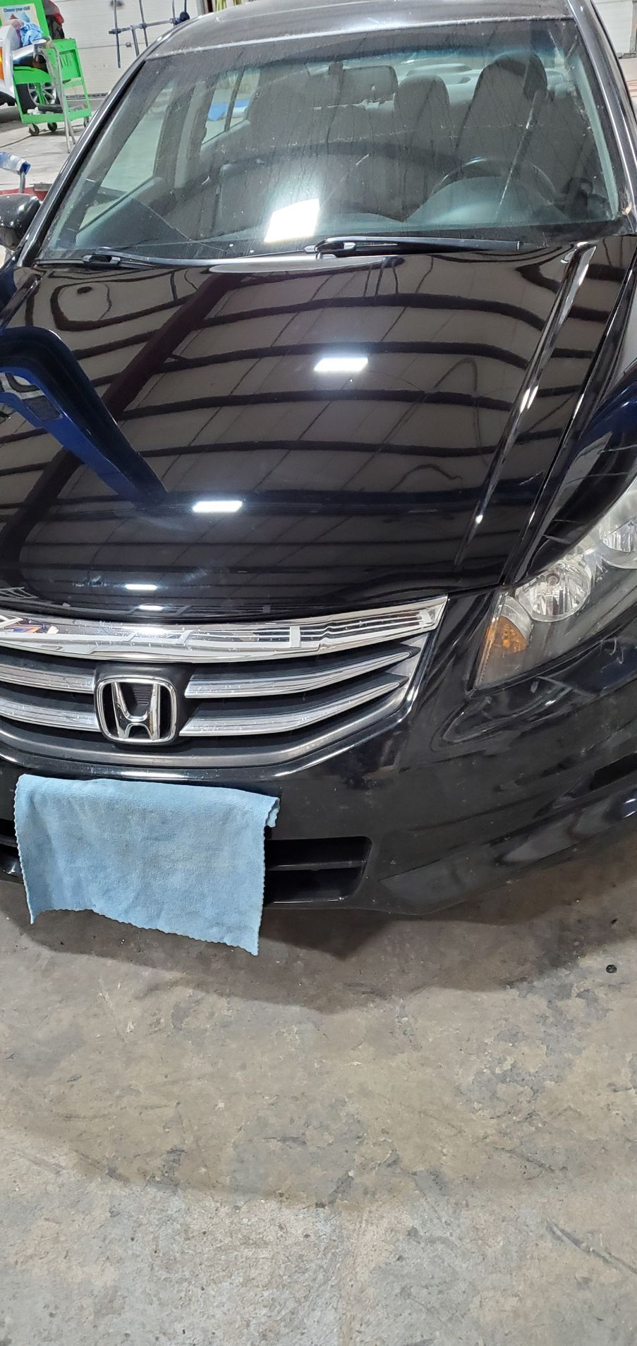 Black Honda Accord car, with a blue cloth hanging from the front bumper, parked on a concrete floor.
