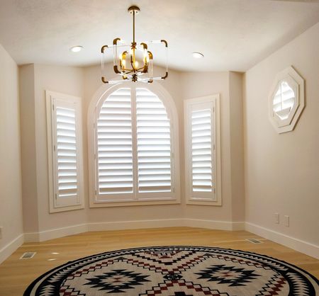 An empty room with shutters and a chandelier hanging from the ceiling