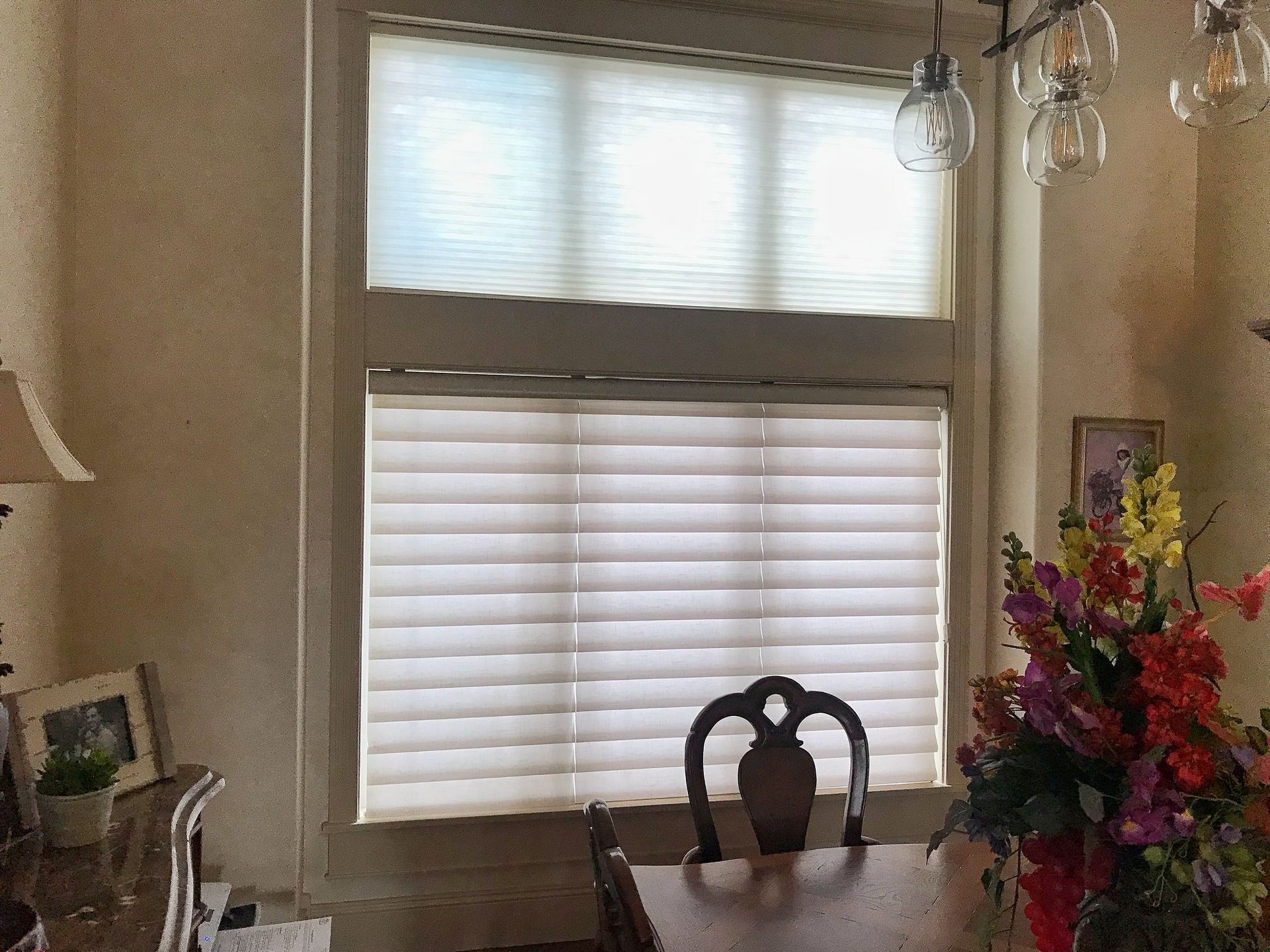 A dining room with a table and chairs and a window with blinds