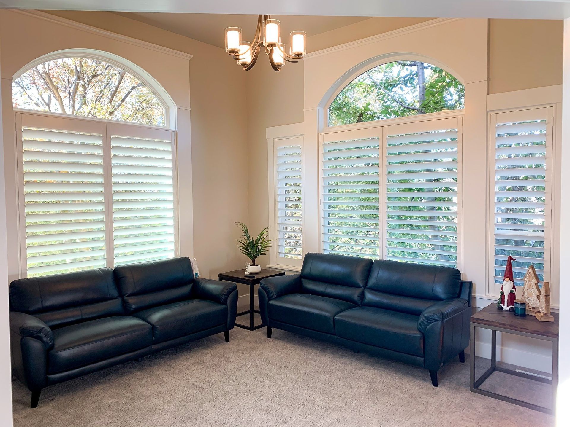 A living room with two black leather couches and a chandelier.