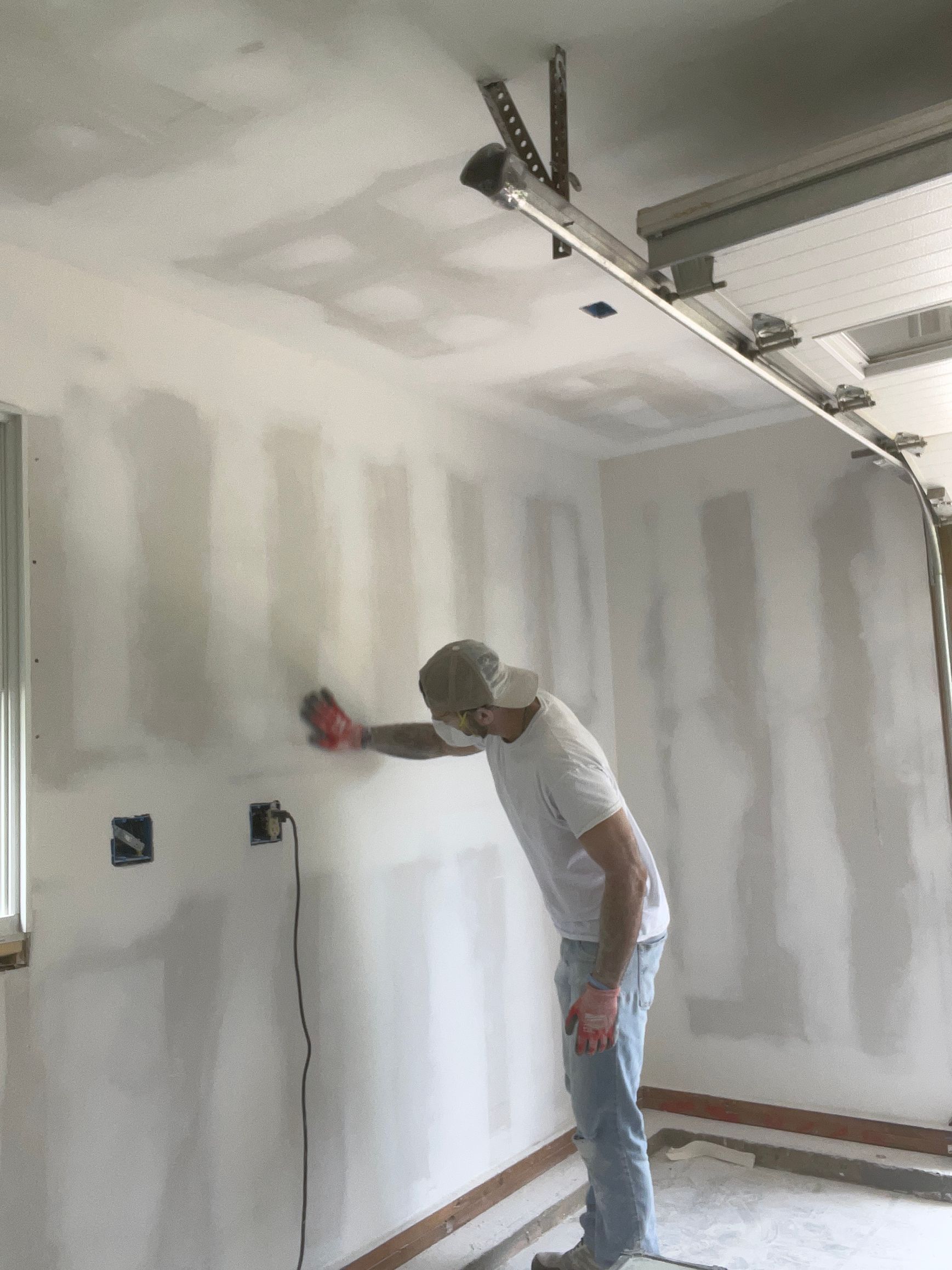 A man is working on a wall in a garage.
