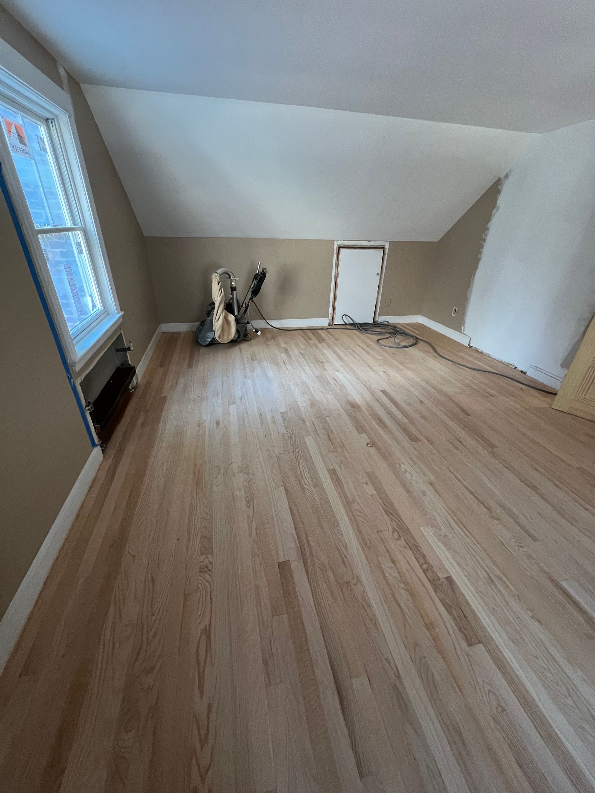 An empty room with hardwood floors and a window.