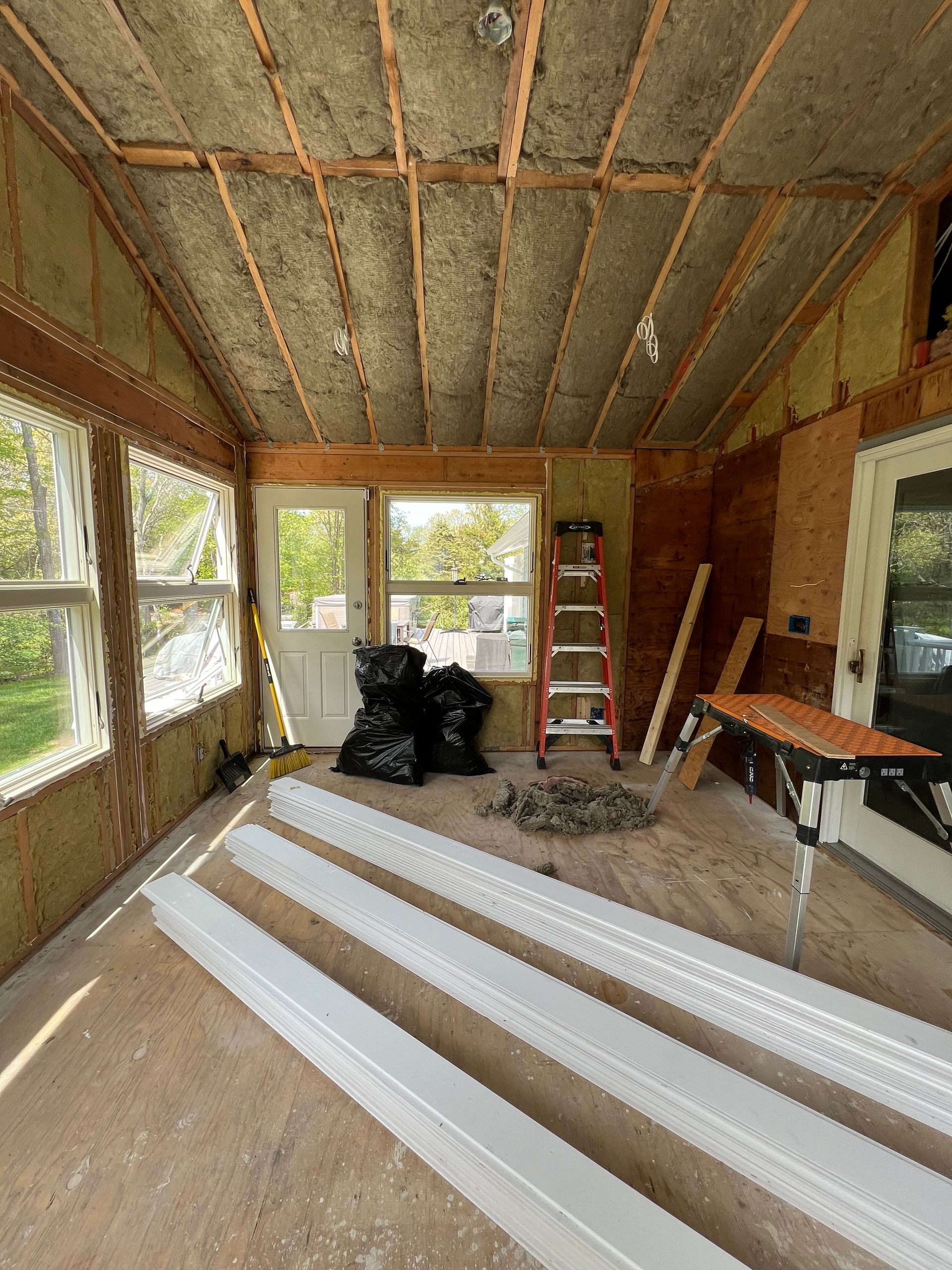 A room with a lot of windows and a ladder in it.