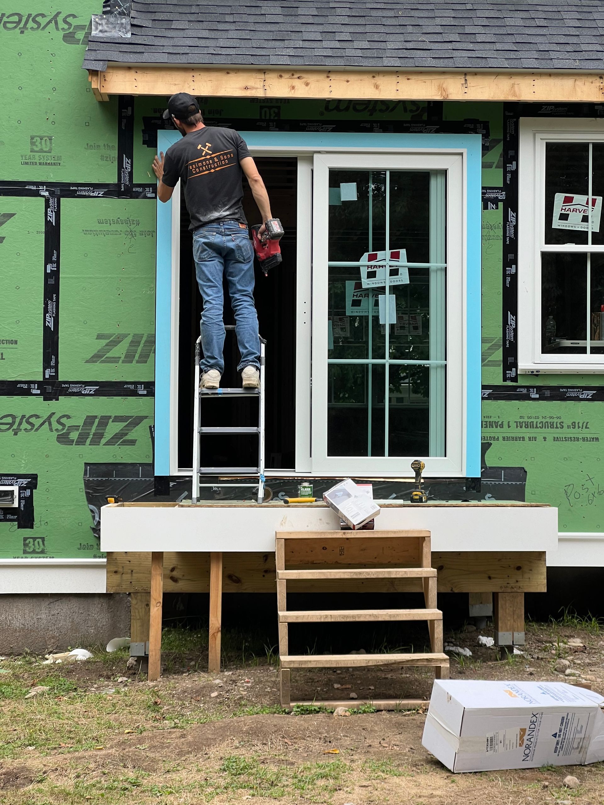 A man on a ladder is working on a window