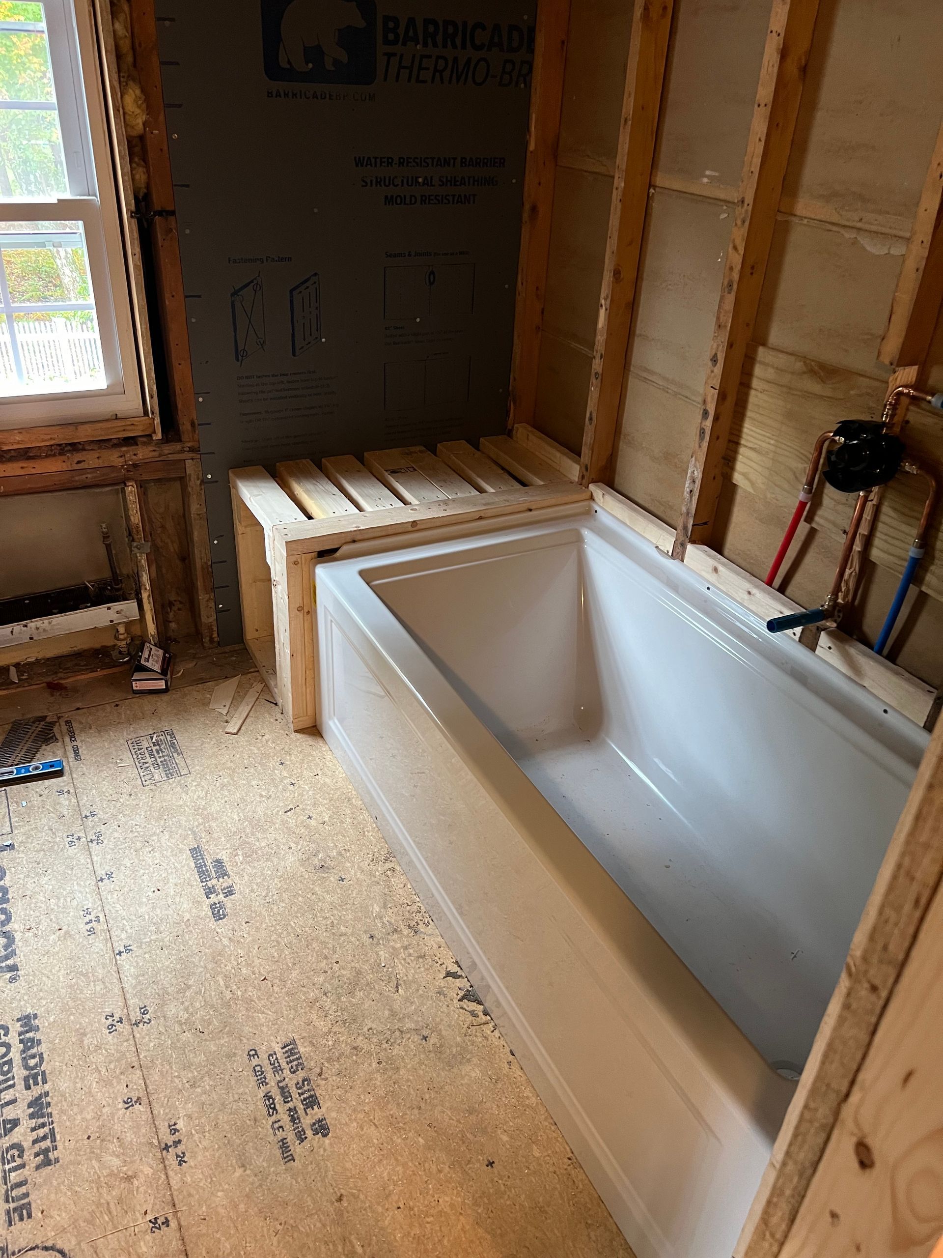 A bathtub is sitting in a bathroom under construction.