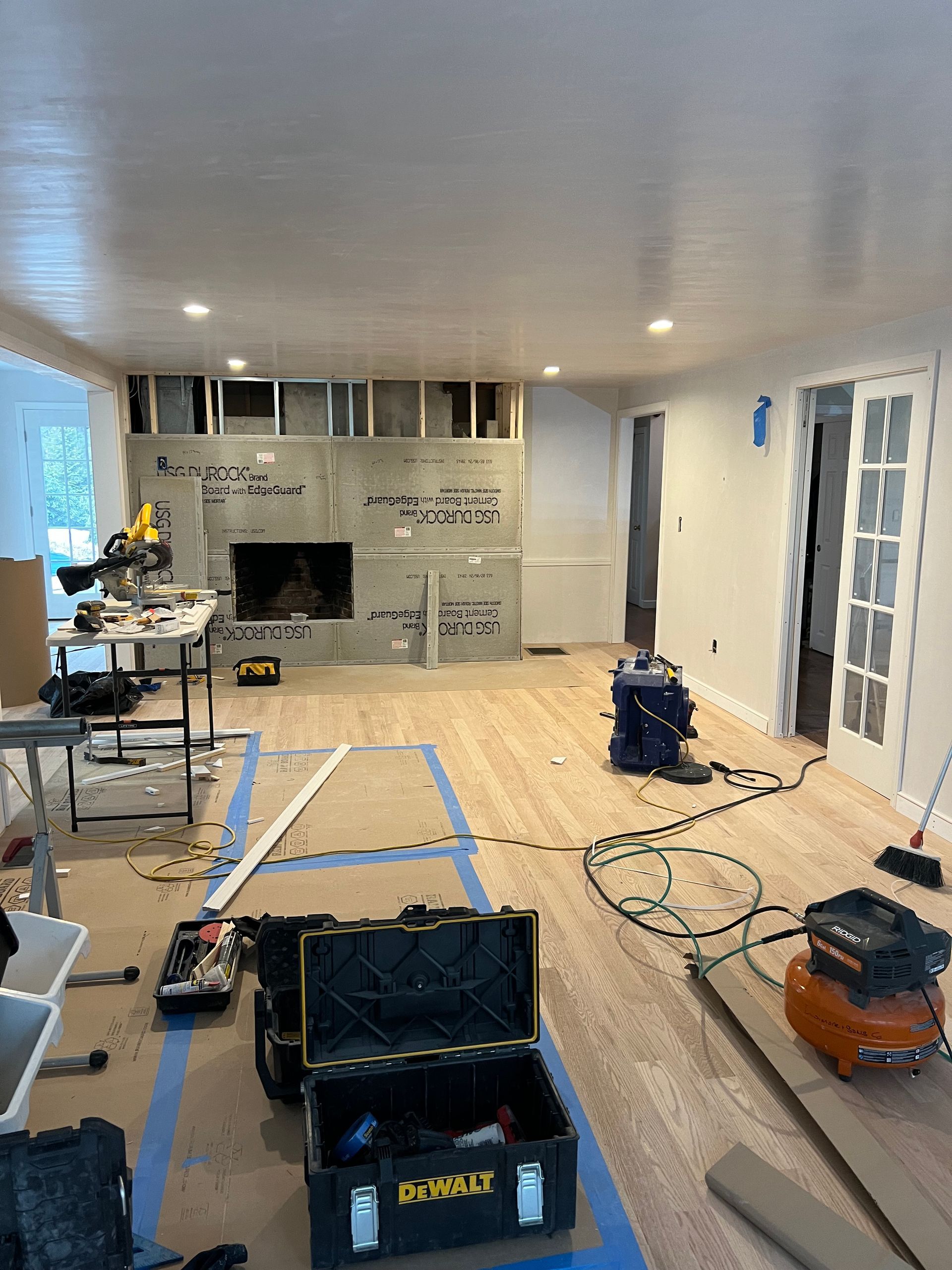 A living room is being remodeled with wood floors and a fireplace.
