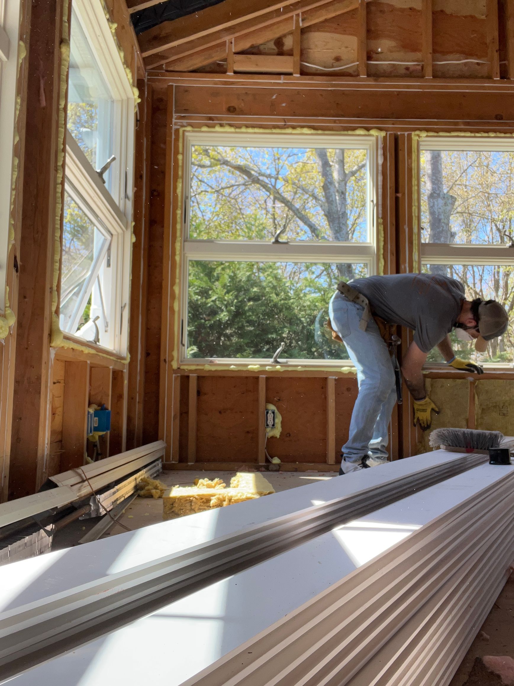 A man is working on a window in a room under construction.