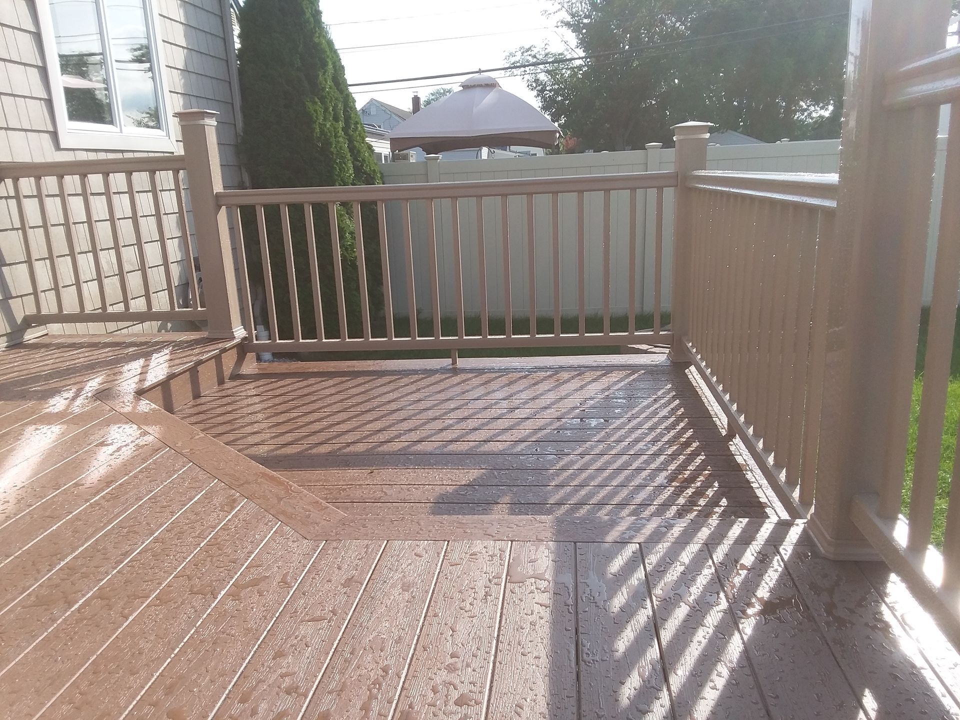 A deck with a railing and a white fence in the background