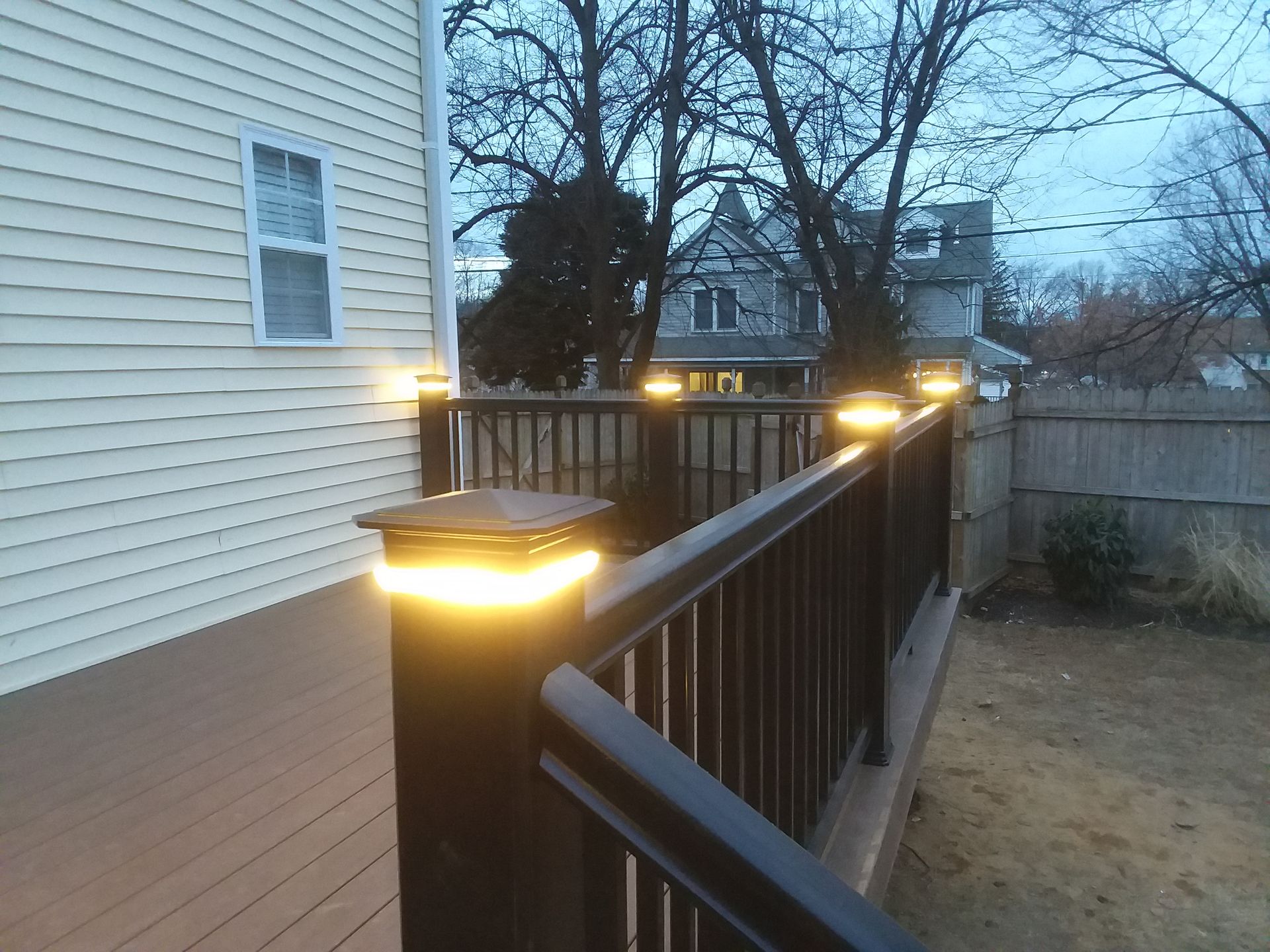 A deck with lights on it and a house in the background