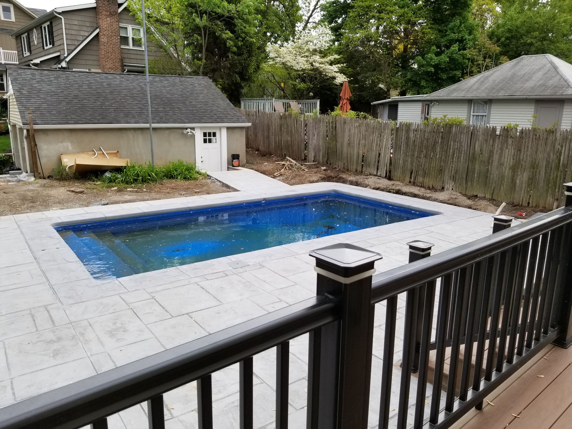 A large swimming pool is in the backyard of a house.